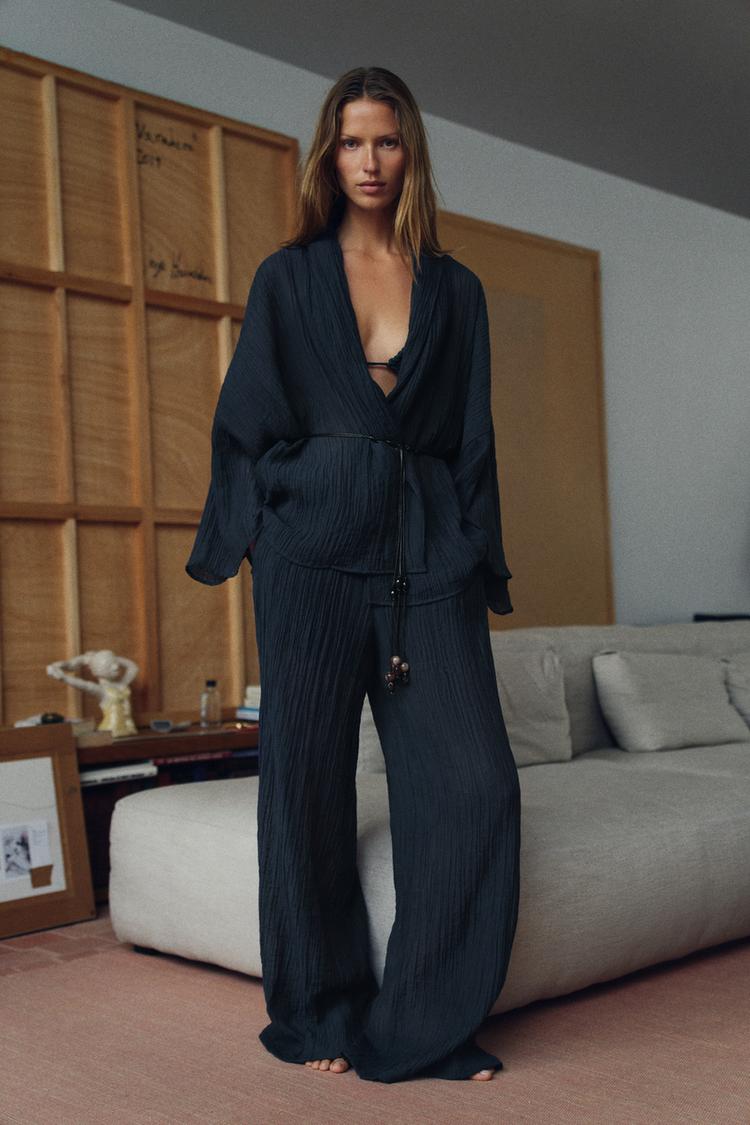 Woman wearing Olive Muse linen two-piece set with V-neck top and wide-leg pants, front view